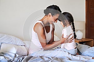 I see so much of myself in her. Shot of a beautiful young mother bonding with her little girl in bed at home.