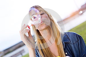 Beautiful young woman having fun with soap bubbles in the park.