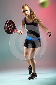 Beautiful young woman playing padel indoor over multicolored background. photo