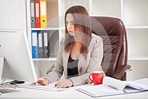 Shot of beautiful young woman sitting at her work desk going through some documents. European business woman working in modern