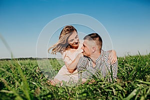 Shot of beautiful young woman sitting outdoors with her boyfriend. Couple in meadow