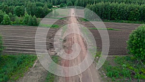 Shot from behind, camera follows man on bicycle cycling on dirt road at sunset