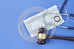 Shot brown gavel, medical stethoscope and mask on a blue background. the concept of medical error.. free copy space for