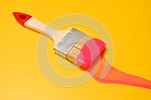 Shot of a brush with pink sticky slime on yellow background. Minimalism in photography, concept creative picture