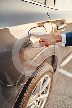 Shot of businessman with his finger on fuel tank of car