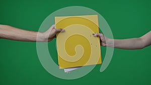 In the shot close up on a green background, chromakey. The woman holds in her hand a yellow folder with documents. She