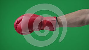 In the shot close up on a green background, chromed. Man in a red, leather boxing glove. He stretches out his hand