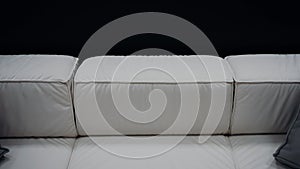 Shot of a comfortable white sofa with two gray pillows on a black background. 4k video.