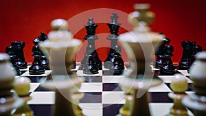 Shot of the confrontation between white and black chess pieces standing on a chessboard
