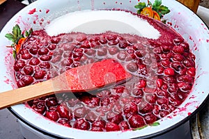 Shot of cooking and preparing homemade cherry jam in a pot. sugar inside the pot.