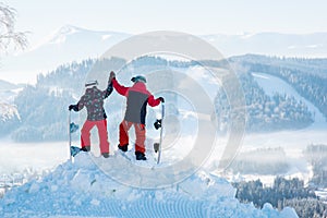 Snowboarders couple standing on top of the mountain