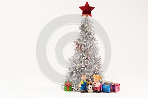 Shot of the cute boy and girl dolls with a puppy gathered under the lush silver Christmas tree