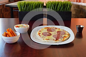 Shot of a delicious pepperoni pizza with cheese  accompanied with carrots and a salad