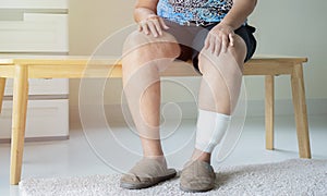 Shot of elder woman sitting on wooden chiar with injured leg. Wounds at the legs