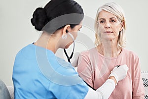 Let me take a listen. Shot of a female doctor examining a patient with a stethoscope.