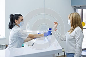 Shot of a female person being measured body temperature with a contactless thermometer by the employee of the reception