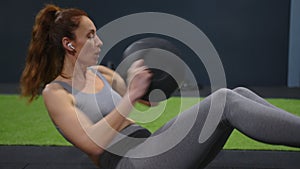 Shot of a fit young woman exercising with pilates black ball at gym. Female athlete doing workout using medicine ball