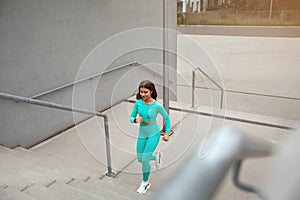 Shot of fitness woman running up on steps. Female runner athlete going up stairs.