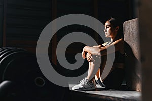 Shot of fitness woman sitting on exercise mat and looking around.