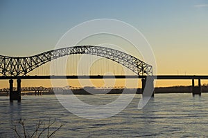 A shot of the flowing water of the Mississippi river with a stunning blue, yellow and red sunset in the sky with a bridge