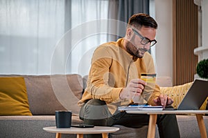 Shot of focused adult man, working online on laptop, sitting in his living room.Concentrated caucasian man, browsing the internet