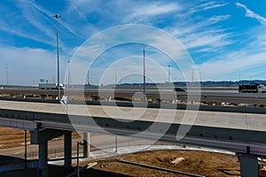 A shot of a freeway filled with cars and Semi trucks and tall power line poles along the highway with yellow winter grass