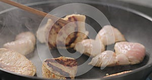 Shot of frying turkey fillet pieces on nonstick pan and turning them with wood spatula