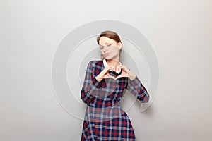 Shot of funny flirtatious young woman making heart gesture and posing