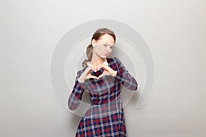 Shot of funny flirtatious young woman making heart gesture and posing