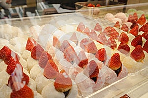 A shot through the glass of various flavors of Daifuku with fresh strawberries inserted in the center.