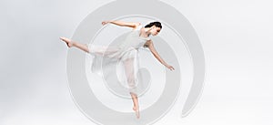 Shot of graceful ballerina dancing on grey background