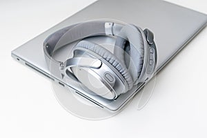 Shot of a gray headphone on a gray laptop isolated on a white background