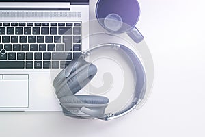 Shot of a gray headphone on a gray laptop next to a blue mug isolated on a white background