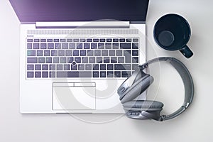 Shot of a gray headphone  on a gray laptop next to a blue mug isolated on a white background