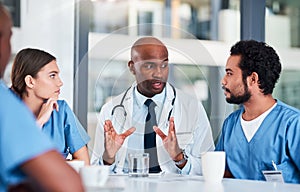 Together they save lives. Shot of a group of focused young doctors having a discussion together while being seated in a