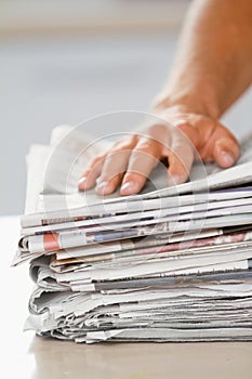 Dont waste paper. Shot of a hand on top of a stack of newspapers.