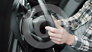 Shot of hands young man driving a new luxury electric car in a car dealership. The buyer selects a car