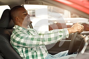 Handsome African man choosing new car at dealership