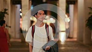 Shot of handsome young asian man traveler walking through night city street