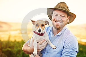 Mens best friend can also be mens best employee. Shot of a happy farmer holding his dog.