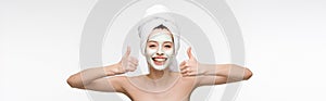 Shot of happy girl with nourishing facial mask and towel on head showing thumbs up isolated on white