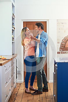 Romance is a dance in the kitchen. Shot of a happy mature couple dancing together at home.