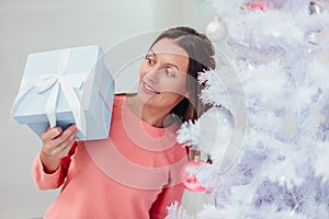 A shot of happy mom, finding a present for herself under christmas tree and now looks at it, smiling and feeling