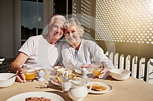 We still start our mornings together. Shot of a happy senior couple having a leisurely breakfast on the patio at home.