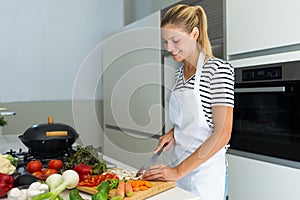 Healthy young woman cutting fresh vegetables in the kitchen at home.