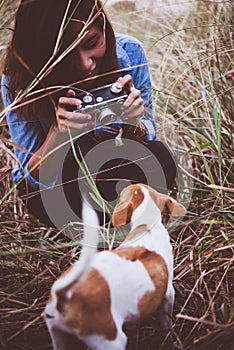 Shot of hipster woman taking a snapshot of her dog on her vintage camera.