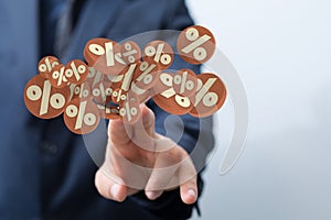 Shot of a human hand reaching for 3D models of percentage symbols on brown coinlike surfaces