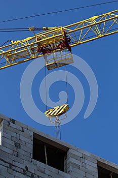 Shot of jib of yellow crane near building partially constructed