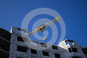 Shot of jib of yellow crane near building partially constructed