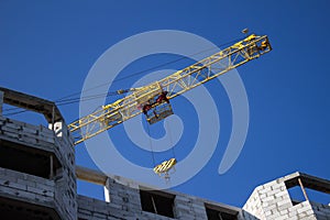 Shot of jib of yellow crane near building partially constructed